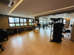 A gym with exercise equipment, large windows, and a wooden floor. - O Melhor de Goiania! Apt de 1 Quarto no coracao do Marista (Goiânia)
