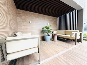 Un espace de détente extérieur moderne, avec un canapé et une table, un pot de fleurs et un mur composé de lattes verticales.