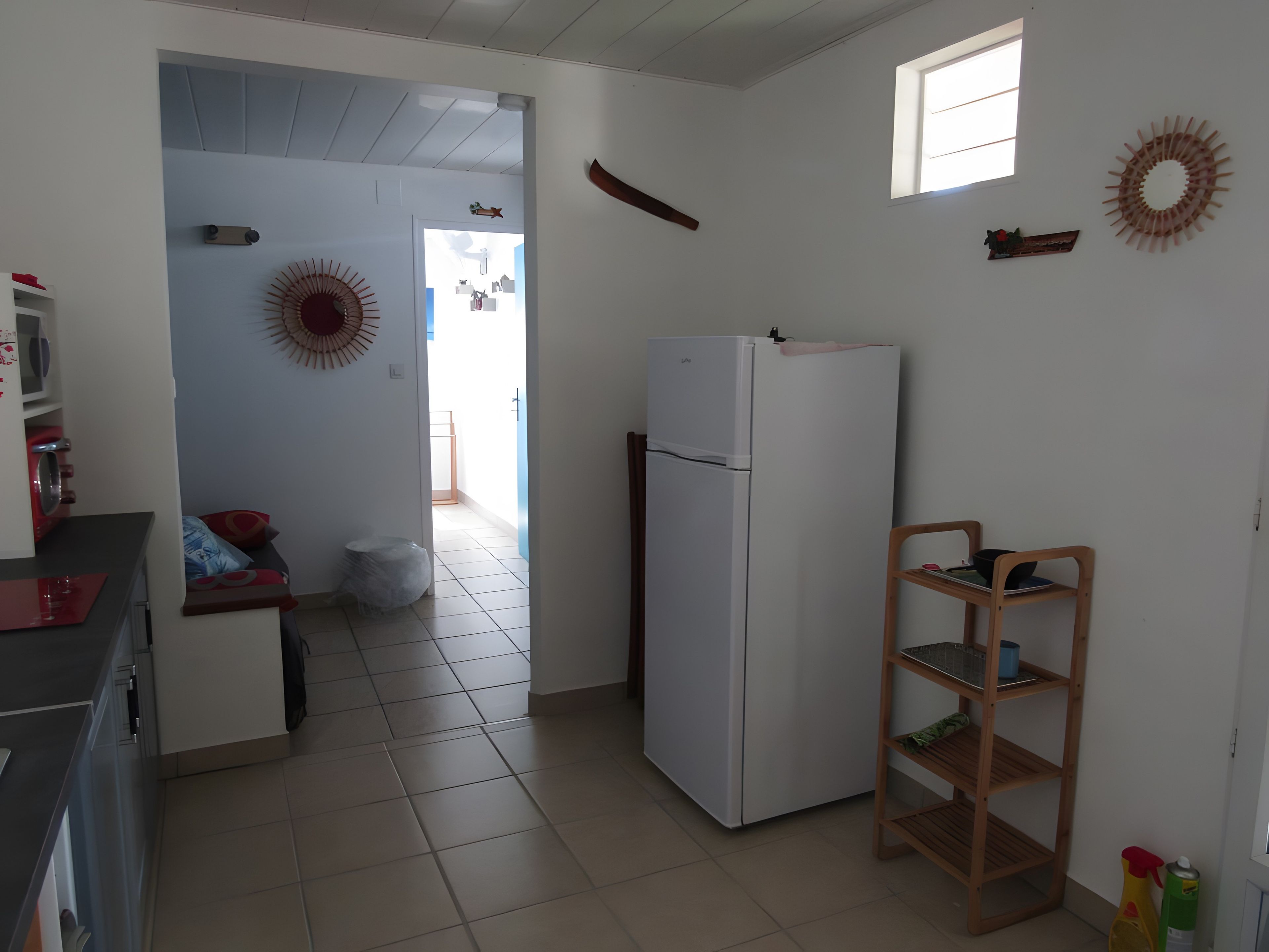 Une cuisine équipée d’un réfrigérateur, d’une étagère en bois et d’une fenêtre.