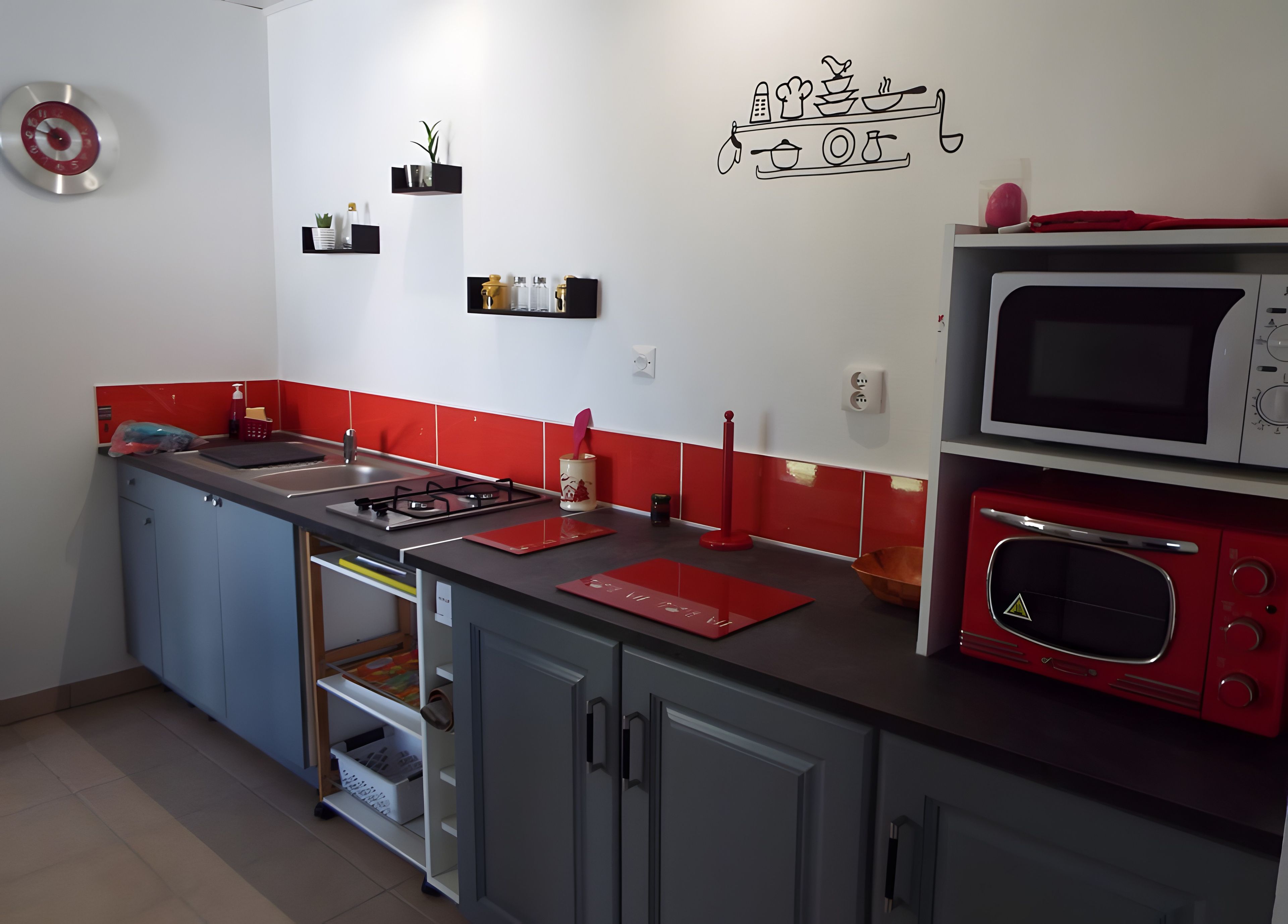 A kitchen with a gas stove, microwave, and red and black countertop.