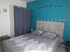 Une chambre à coucher avec un lit, une table de chevet, une chaise, un rideau et un mur décoré d’étoiles.