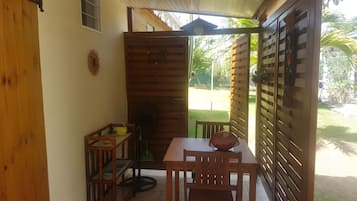 Un patio couvert comprenant une table et des chaises, un ventilateur et un meuble en bois.