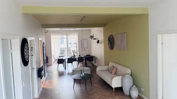 A spacious living area with a herringbone floor, a dining table with chairs, a sofa, and a coffee table.