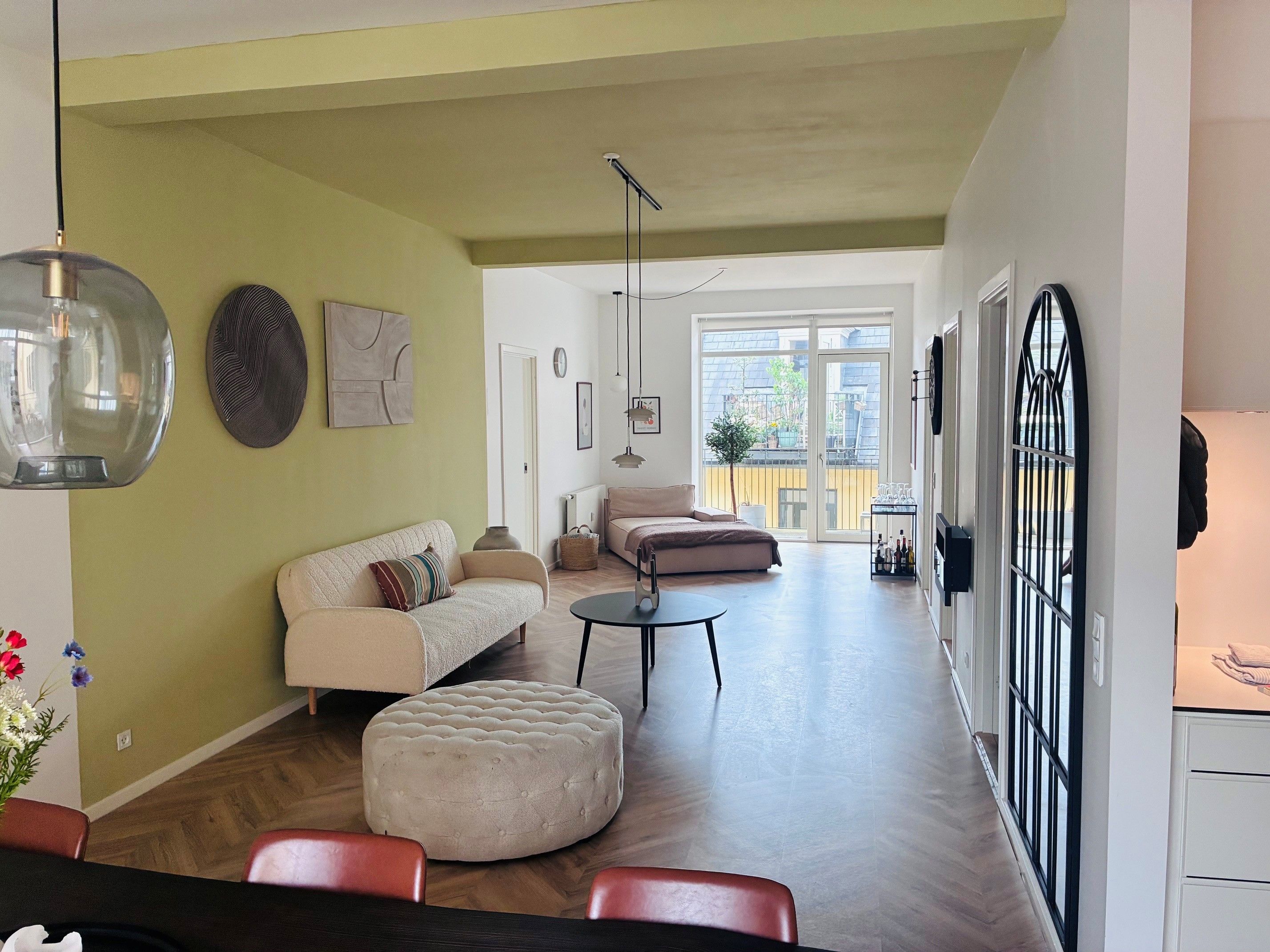 Ein modernes Wohnzimmer mit einer Couch, Hocker und Essbereich.