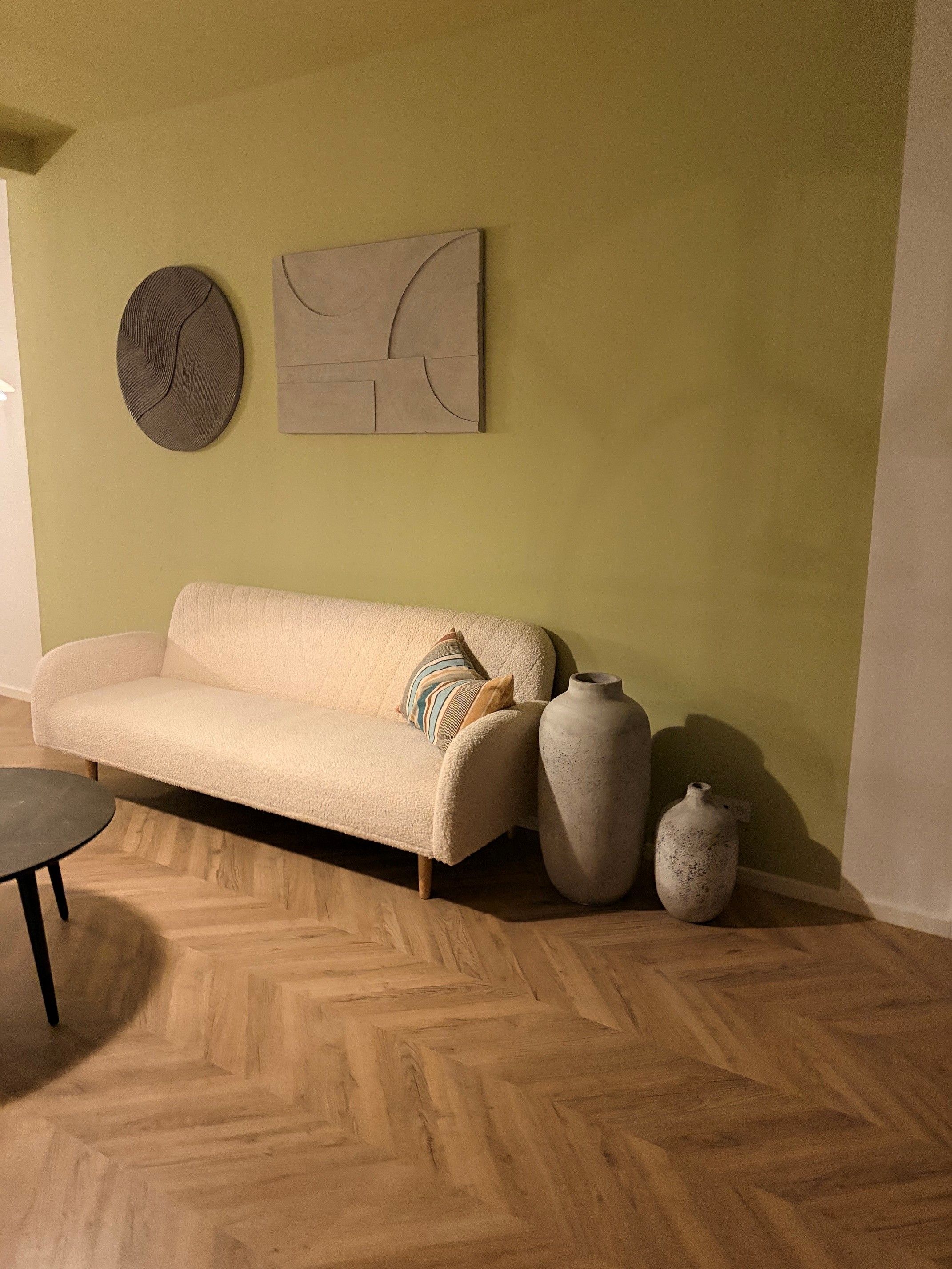 Ein Zimmer mit einer Couch, zwei Vasen und einer runden Wanddekoration.