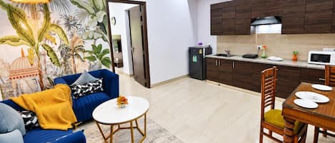 A living room with a sofa, coffee table, and a dining area with a table and chairs.