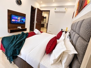 Ein Hotelzimmer mit Bett, Fernseher, Wand-Klimaanlage und einer Tür zu einem Badezimmer.