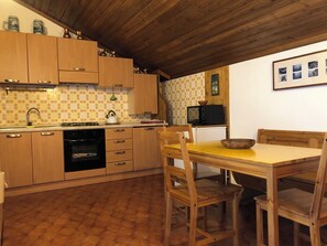 A kitchen with wooden cabinets, a gas stove, a microwave, and a dining table with chairs. - New Listing (Pieve di Cadore)