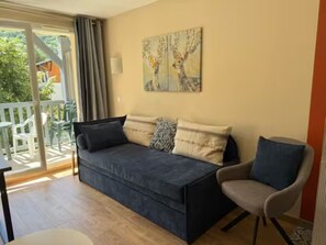 Ein möbliertes Wohnzimmer mit einer Couch, einem Sessel und einem Bild an der Wand.