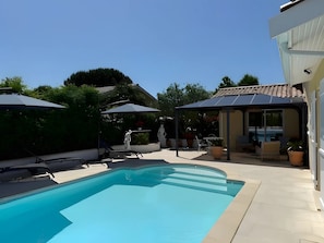 A swimming pool with sun loungers and umbrellas, surrounded by a patio area with outdoor furniture. - Guest room 'Chambre Boléro' with shared terrace, Wi-Fi and air conditioning (Gujan-Mestras)