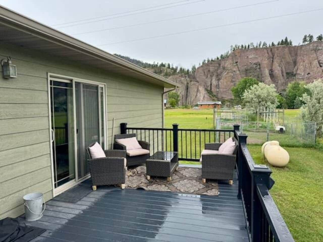 Une terrasse couverte, aménagée avec du mobilier d’extérieur, une porte-fenêtre coulissante et une vue sur un paysage montagneux.