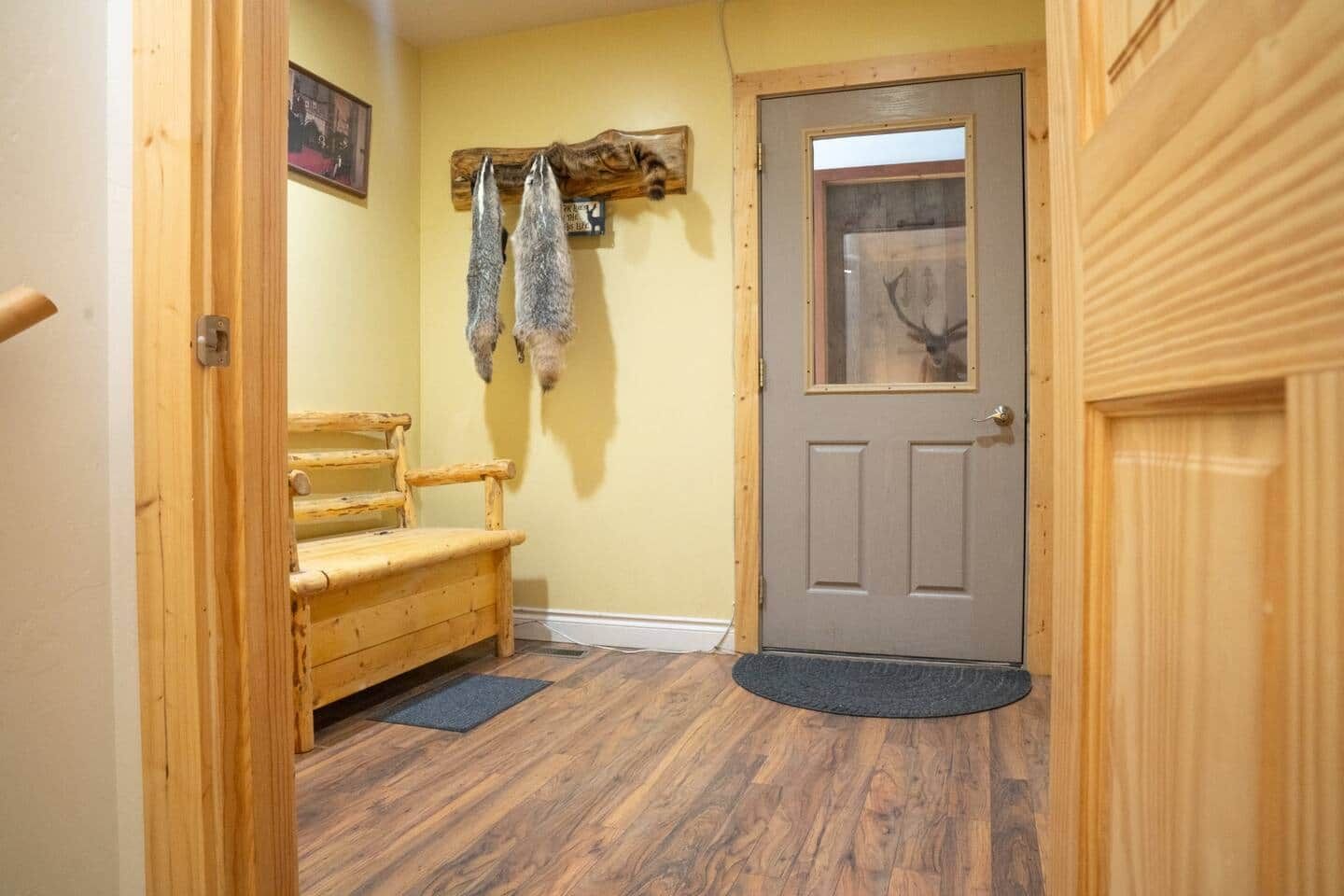 A wooden bench, a door with a glass panel, and a wall-mounted deer head.