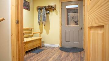 A wooden bench, a door with a glass panel, and a wall-mounted deer head.