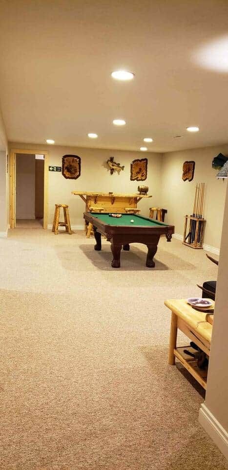 A room with a pool table, a wooden bench, and a door leading to another area.