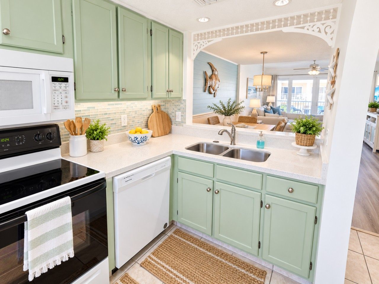 A kitchen with a microwave, stove, sink, and green cabinets.