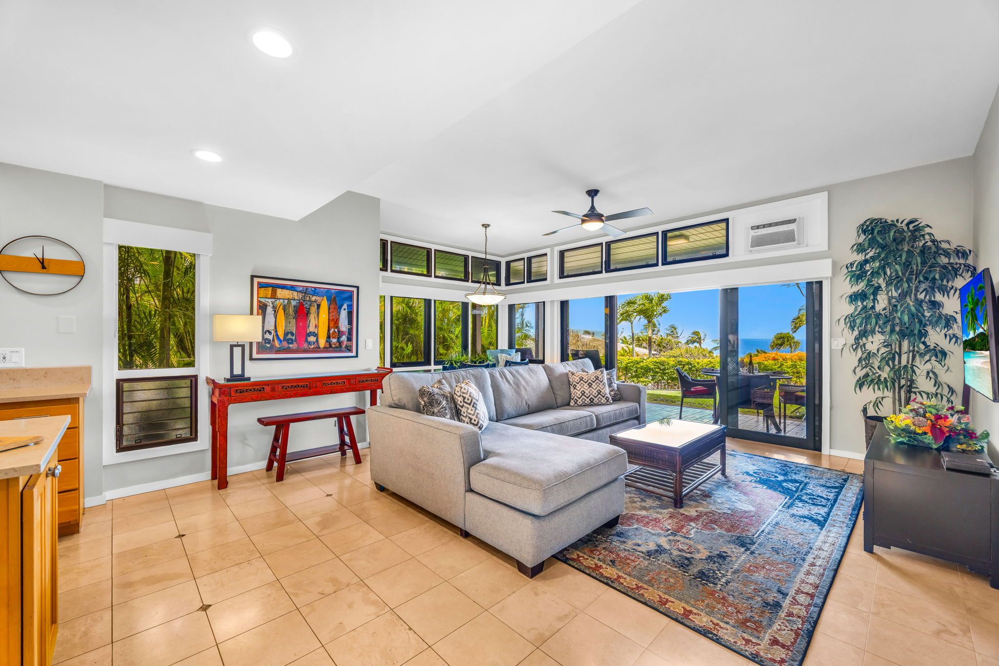 A spacious living room with a sectional sofa, a dining area with a wooden table, and a large window offering a view of the outdoors.