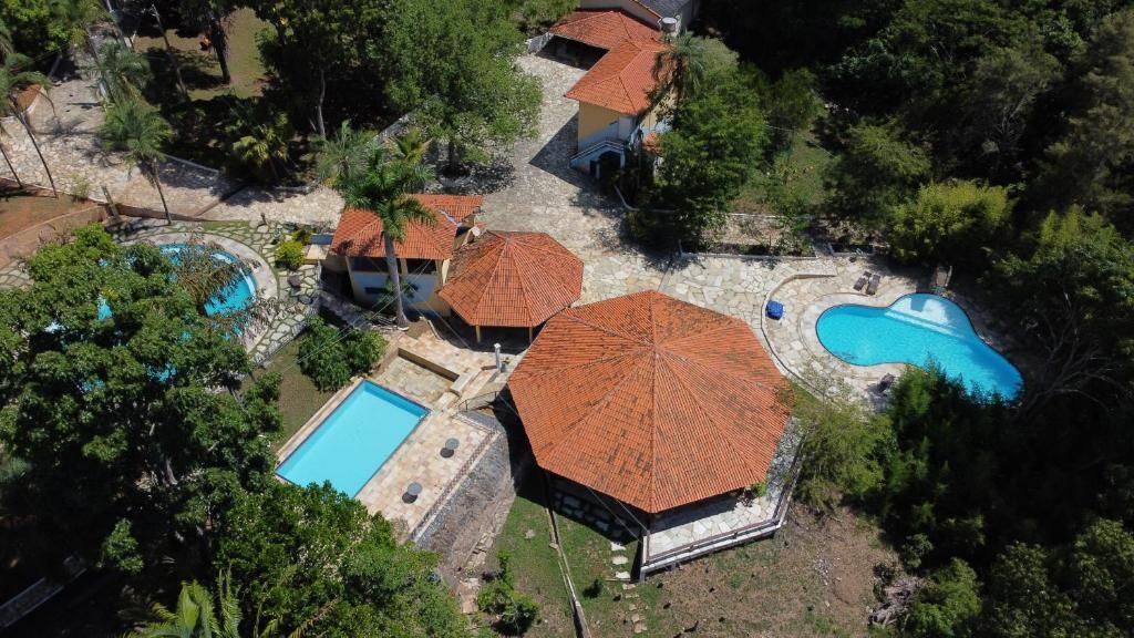 Vista aérea de una propiedad con varias piscinas, zonas de estar exteriores cubiertas y un edificio central con un techo distintivo.