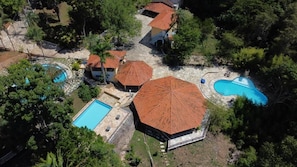An aerial view of a property with multiple swimming pools, covered outdoor seating areas, and a central building with a distinctive roof. - Pousada Paraíso dos Sonhos (Corumbá de Goiás)