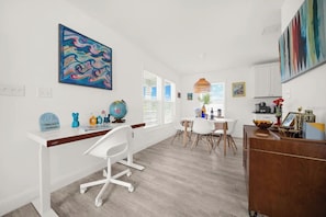Una cocina moderna con armarios blancos, encimera de madera y un comedor con mesa y sillas blancas.