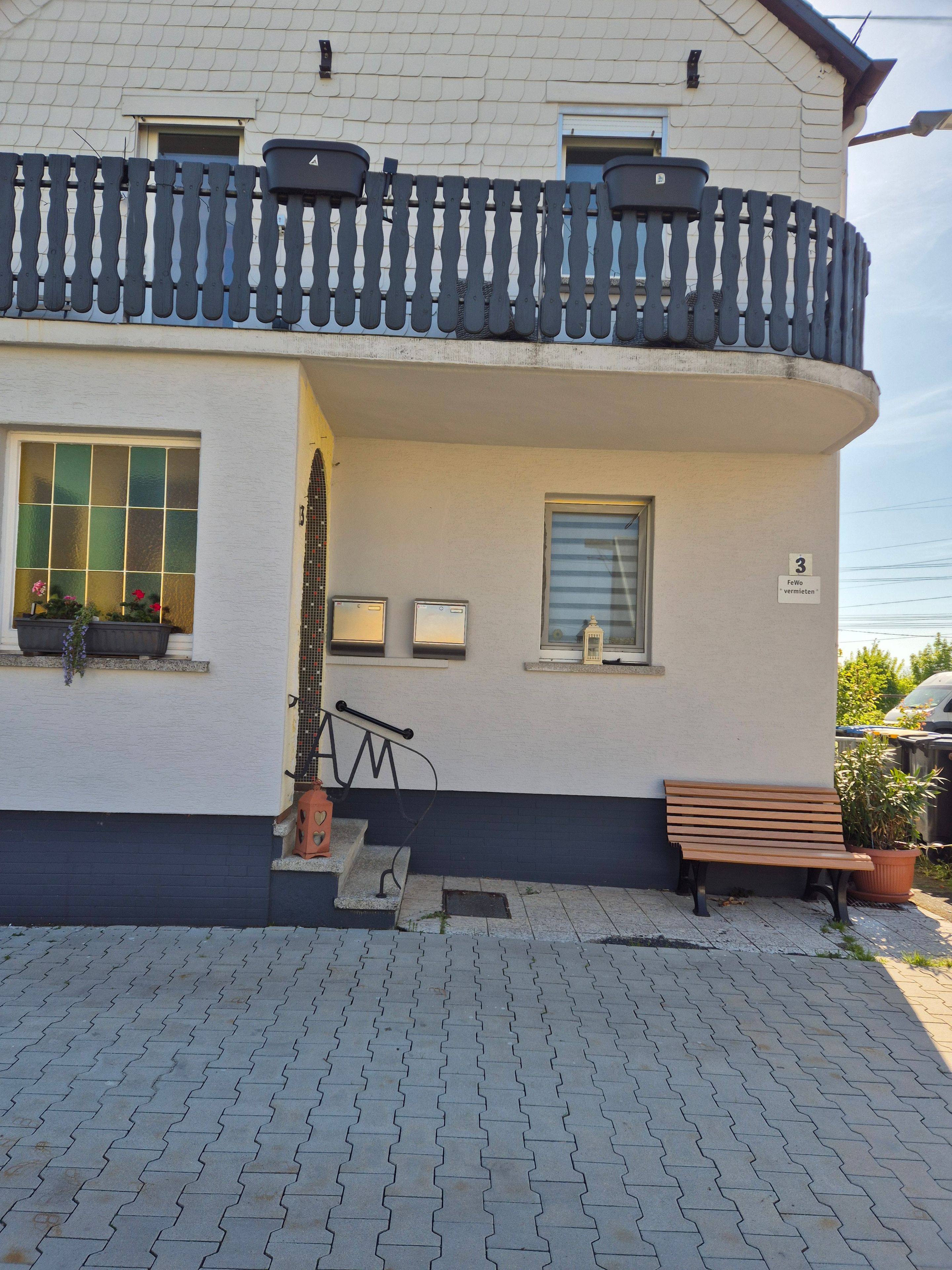 Ein Gebäude mit Balkon, einer Bank und einem Blumentopf.