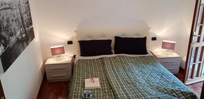 Ein Schlafzimmer mit einem Bett, zwei Nachttischen, einer Wandlampe und einem gerahmten Bild.