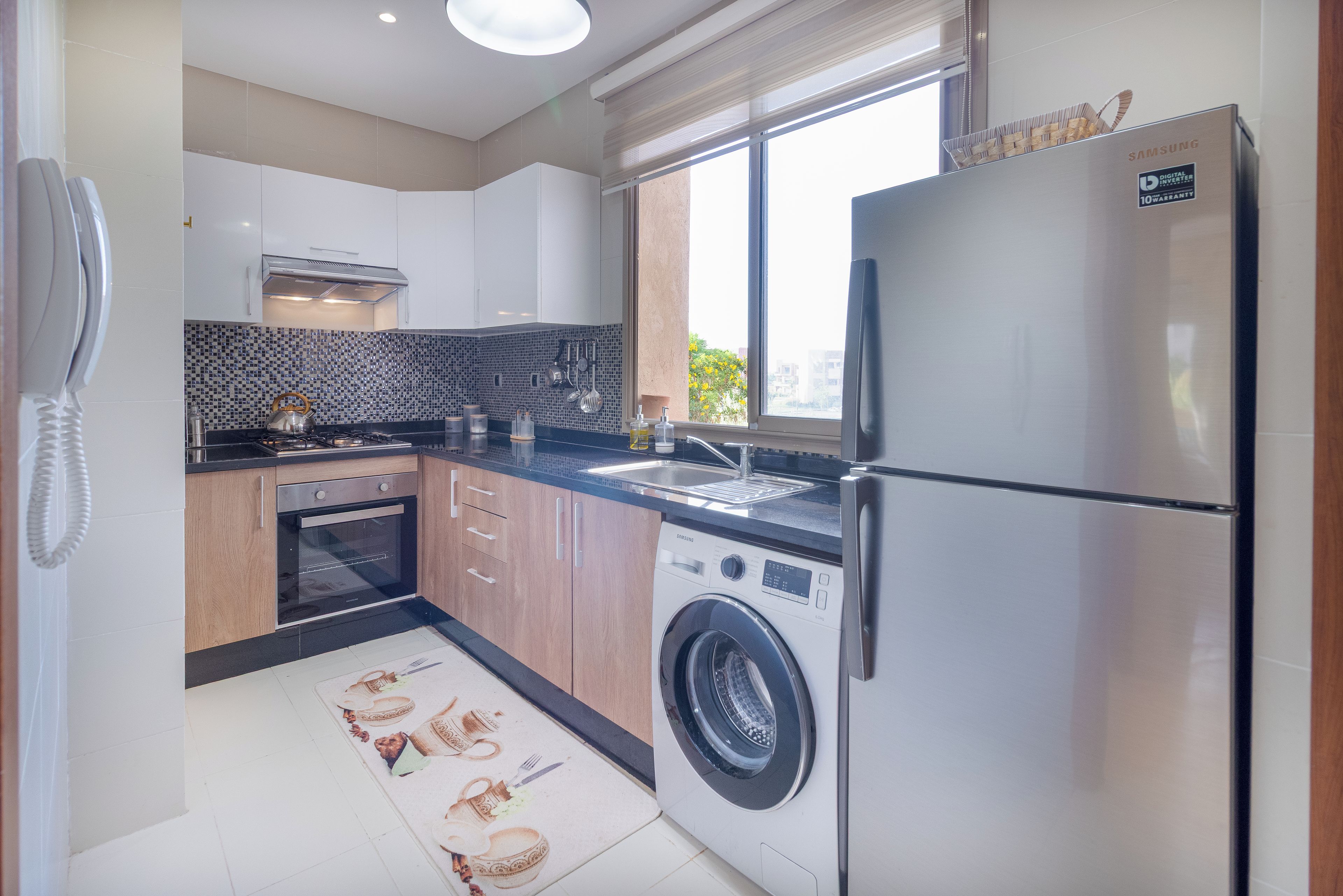 Eine moderne Küche mit Einbauwaschmaschine, Kühlschrank und einem Fenster für natürliches Licht.
