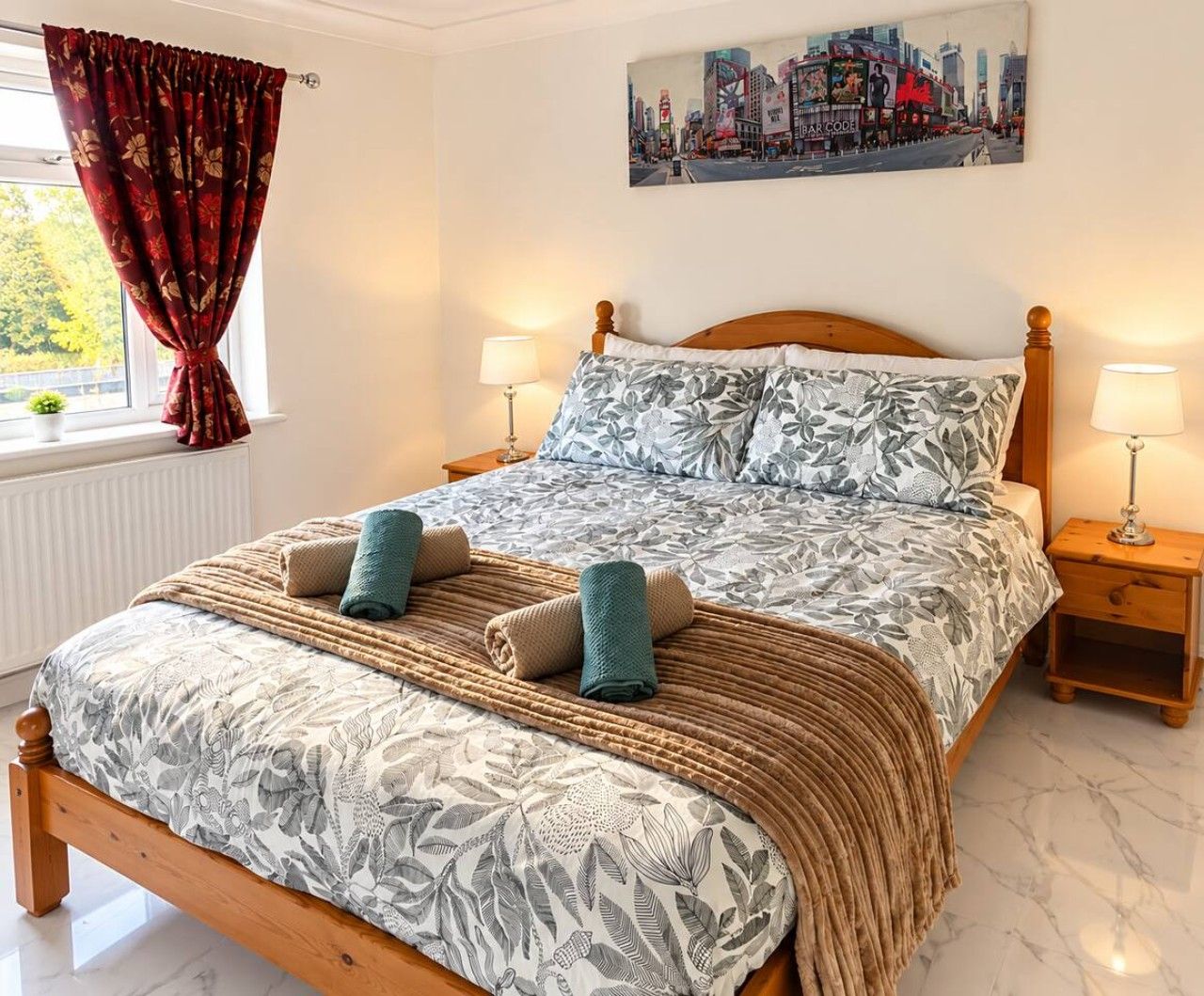 Un letto rifatto con cura, una coperta a fiori, due cuscini e una coperta in tessuto intrecciato.