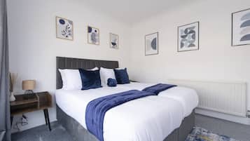 Un dormitorio con cama, mesitas de noche y decoración en la pared.