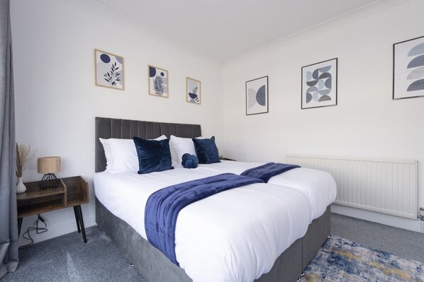 Un dormitorio con cama, mesitas de noche y decoración en la pared.