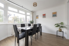 Un comedor con una mesa y sillas, una planta en maceta y una obra de arte en la pared.
