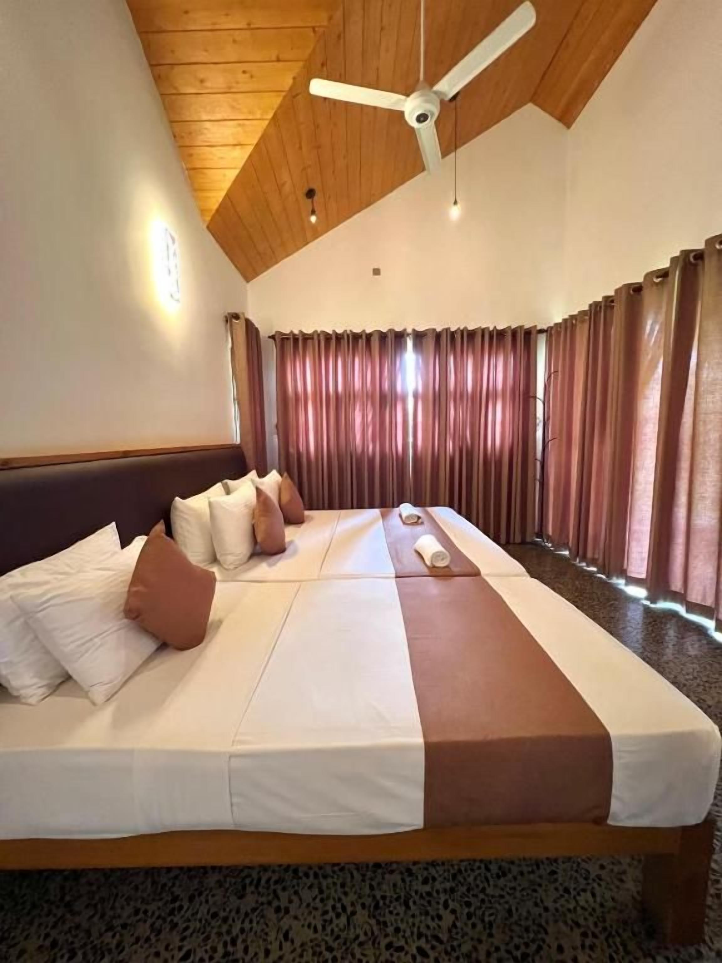 Une chambre d’hôtel avec un grand lit, un plafond en bois et un ventilateur de plafond.