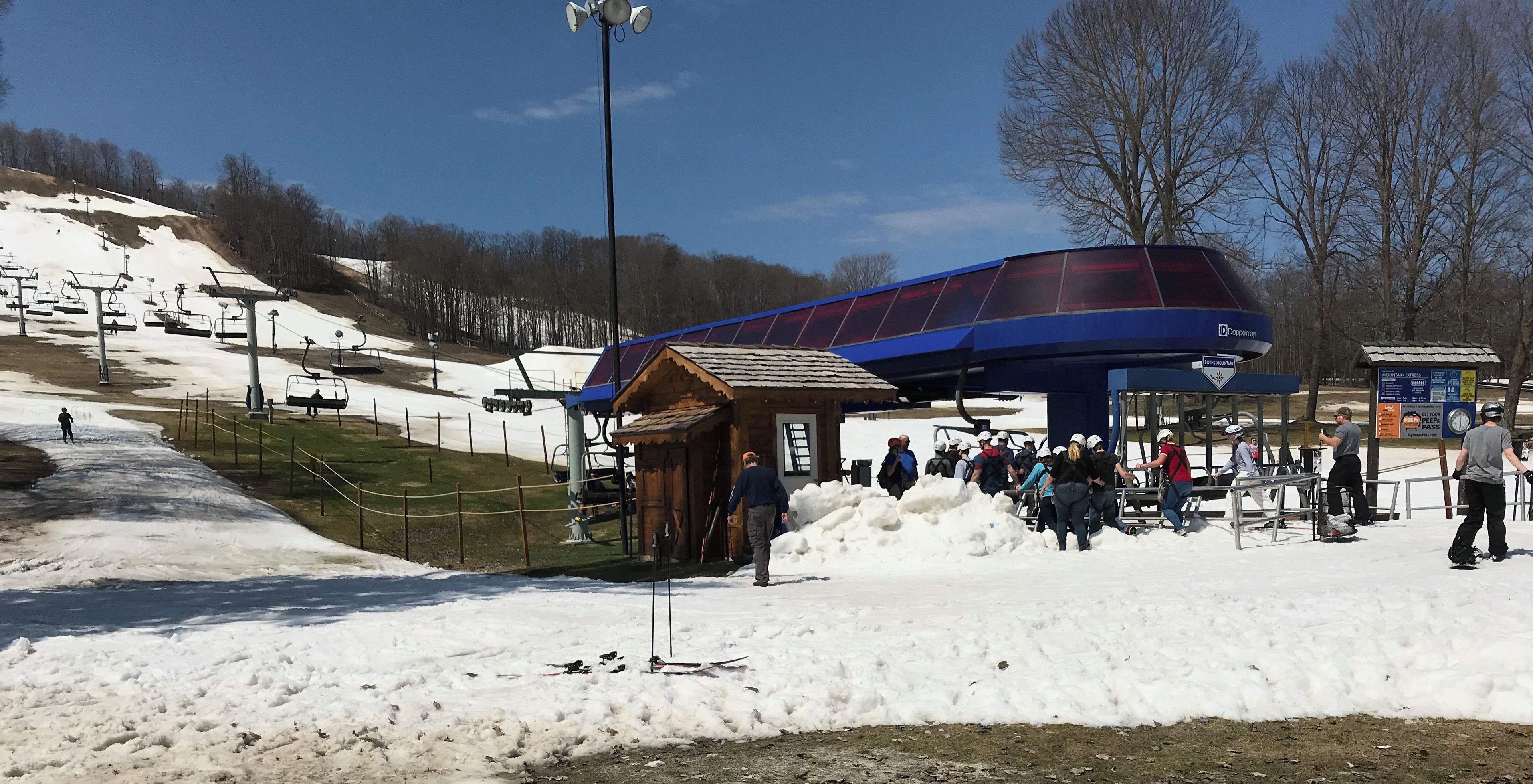 Une station de ski dotée d'un télésiège, d'un abri en bois et d'une piste enneigée.