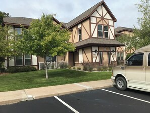 Un bâtiment à deux étages avec une façade de style Tudor, un parking et un arbre au premier plan.