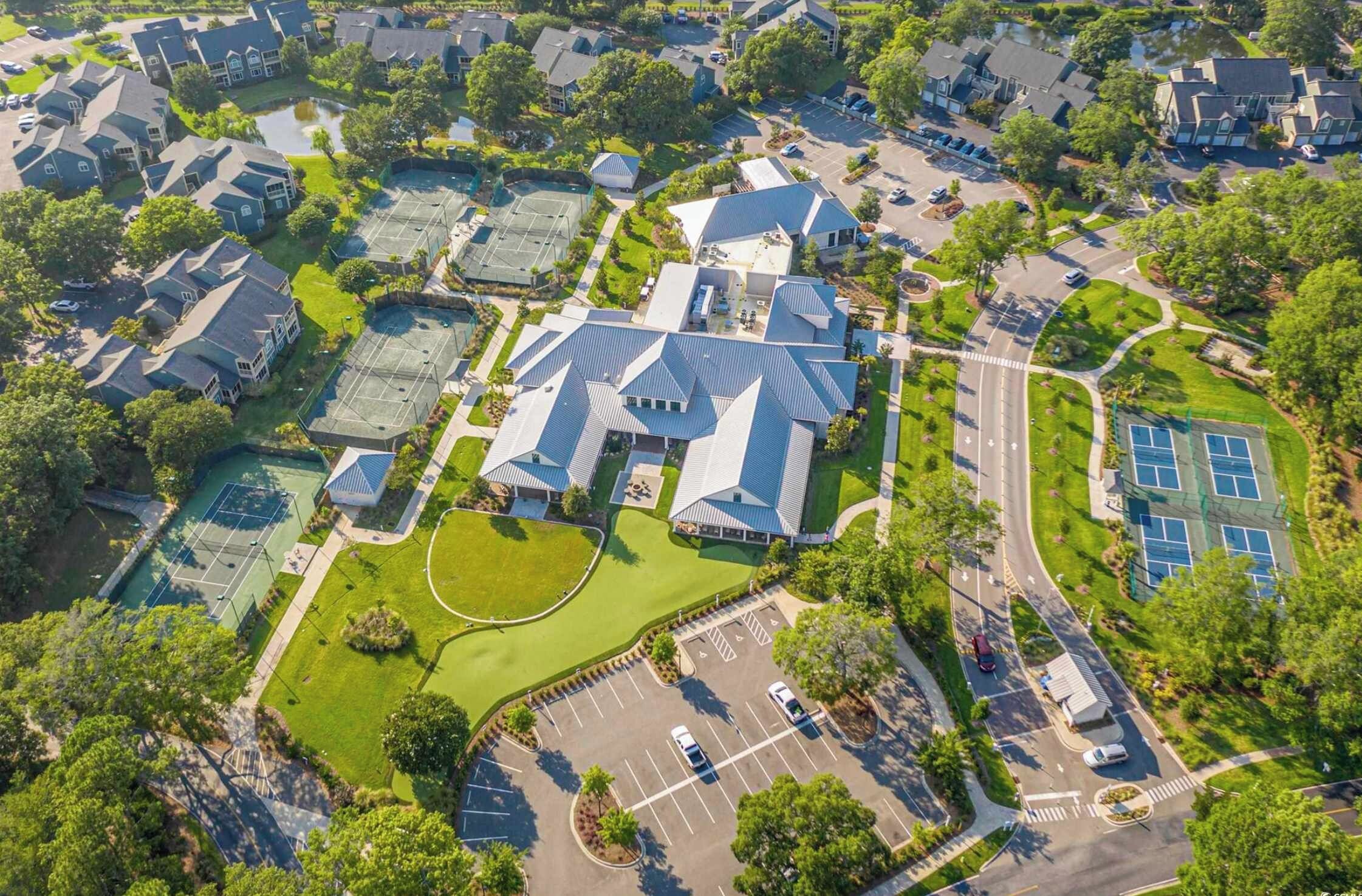 Vue aérienne d’un quartier résidentiel avec des maisons, un court de tennis et un parking.