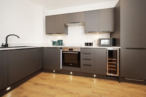 Eine moderne Küche mit dunklen Schränken, einem Backofen, einer Mikrowelle und einem Weinkühler.