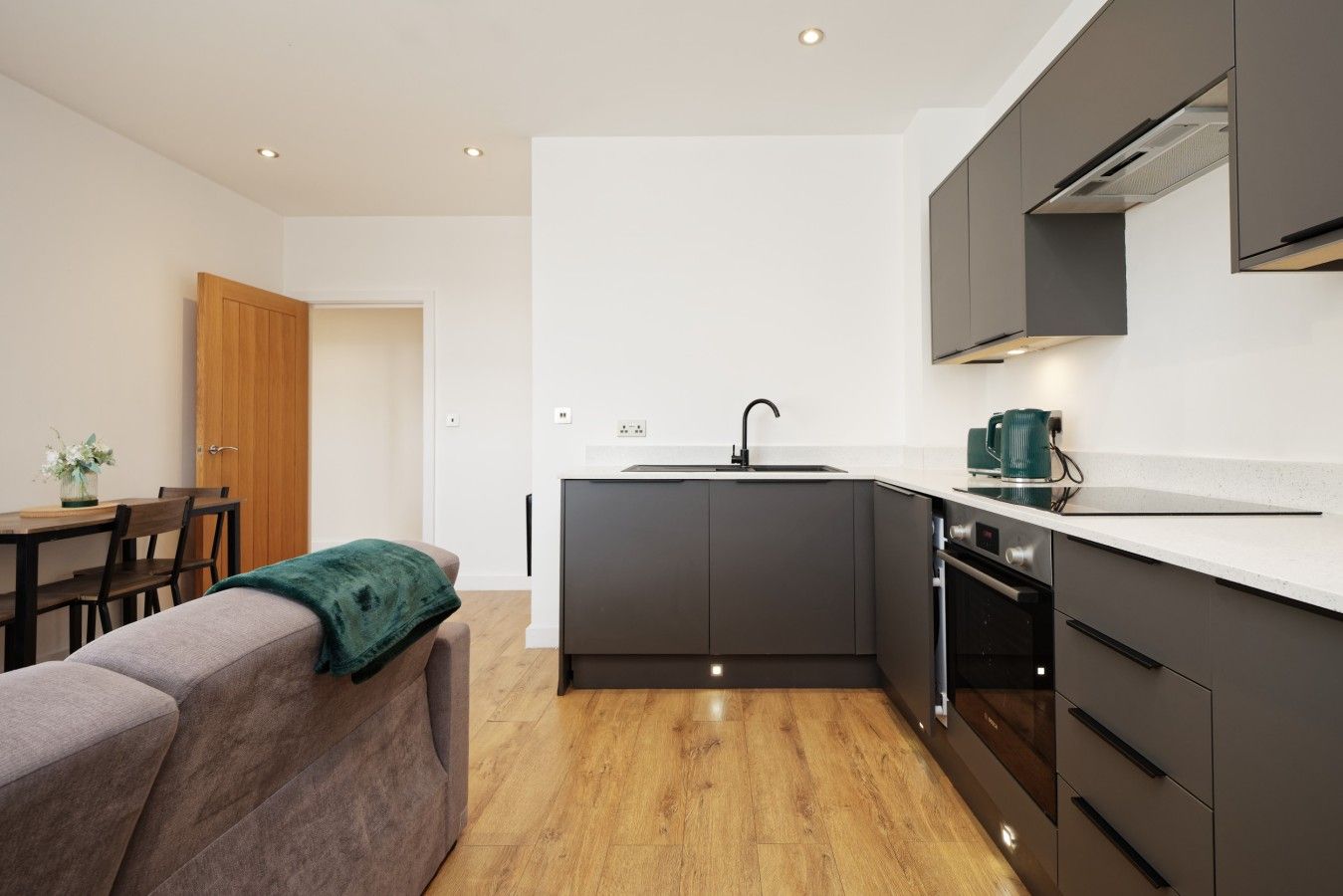 A modern kitchen with a central island, dark cabinetry, and a white countertop.