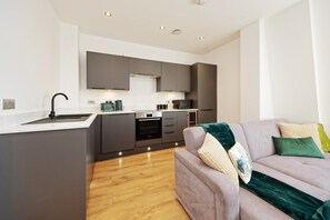 A modern kitchen with grey cabinets, a built-in oven, and a sink. - Pearl Place | 4 Beds | Sleeps 8 | Ramsgate (Kent)