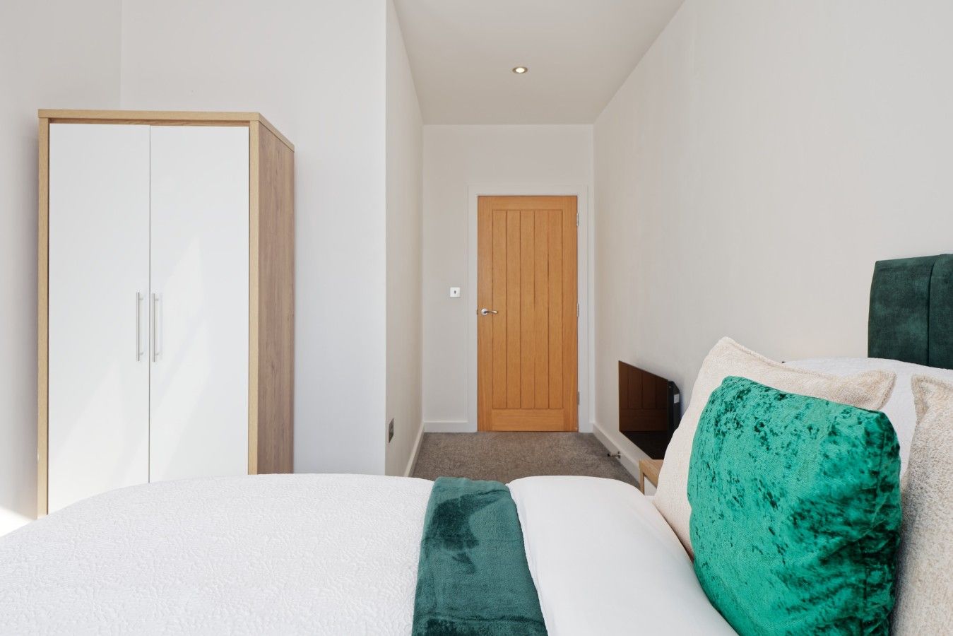 A bedroom with a bed, a wardrobe, a door, and a headboard.