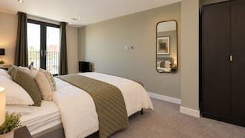 Een hotelkamer met een bed, een grote spiegel, een kledingkast en een raam met gordijnen.