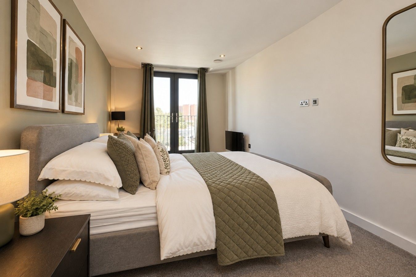 A modern bedroom with a bed, bedside table, lamp, and artwork.