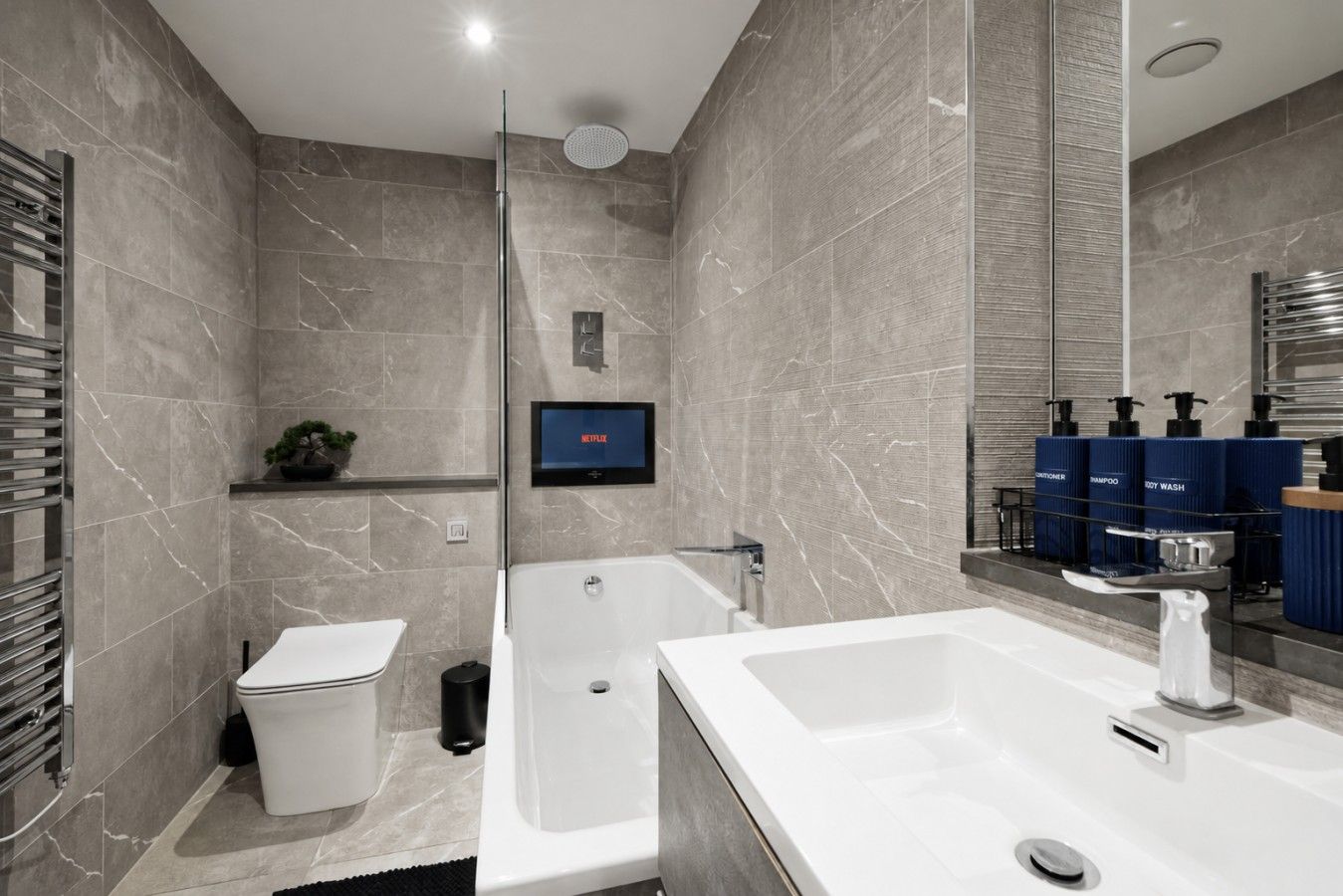 A modern bathroom with a bathtub, toilet, and sink.