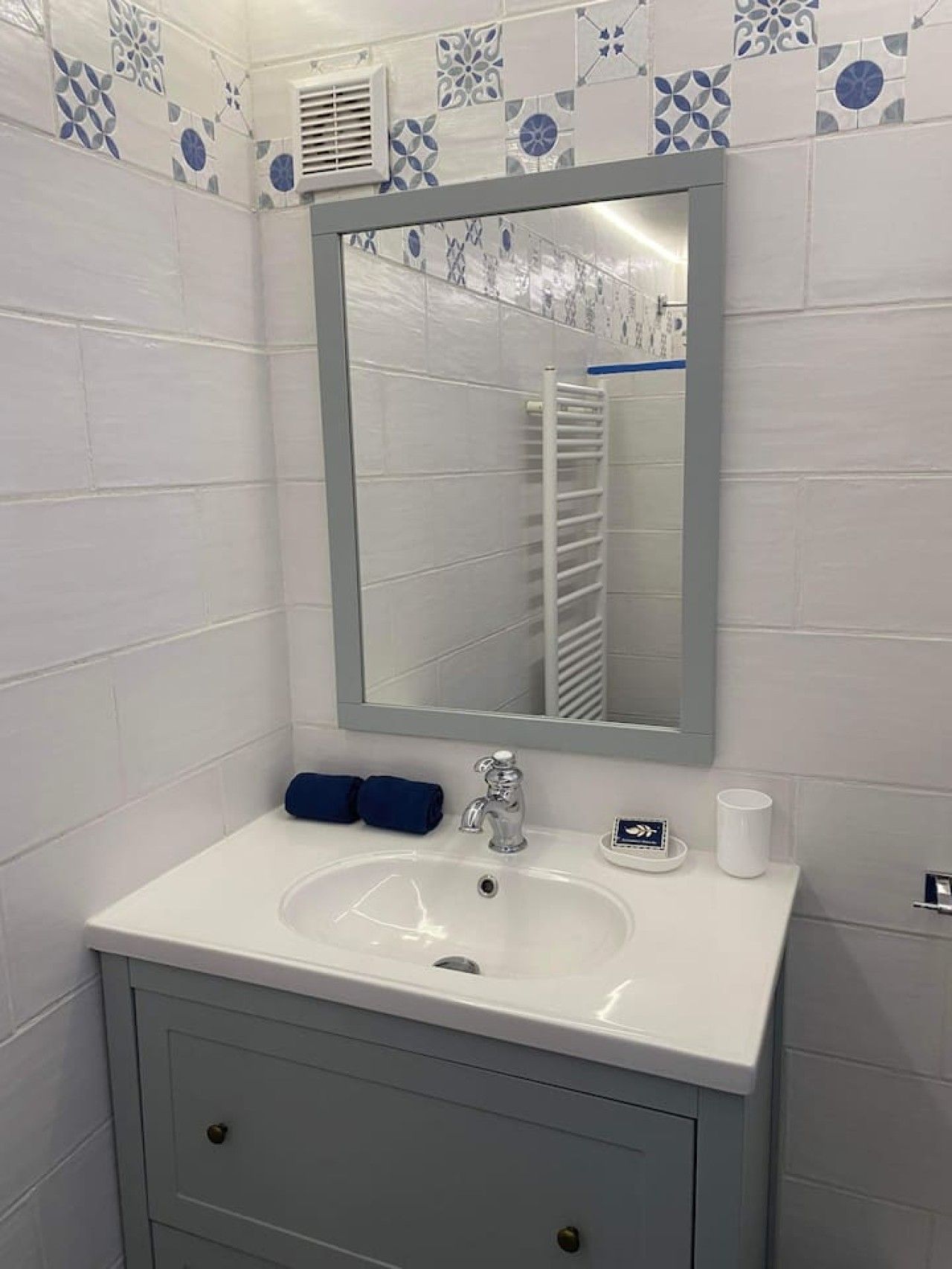 A bathroom with a white sink, a mirror, and a towel rack.