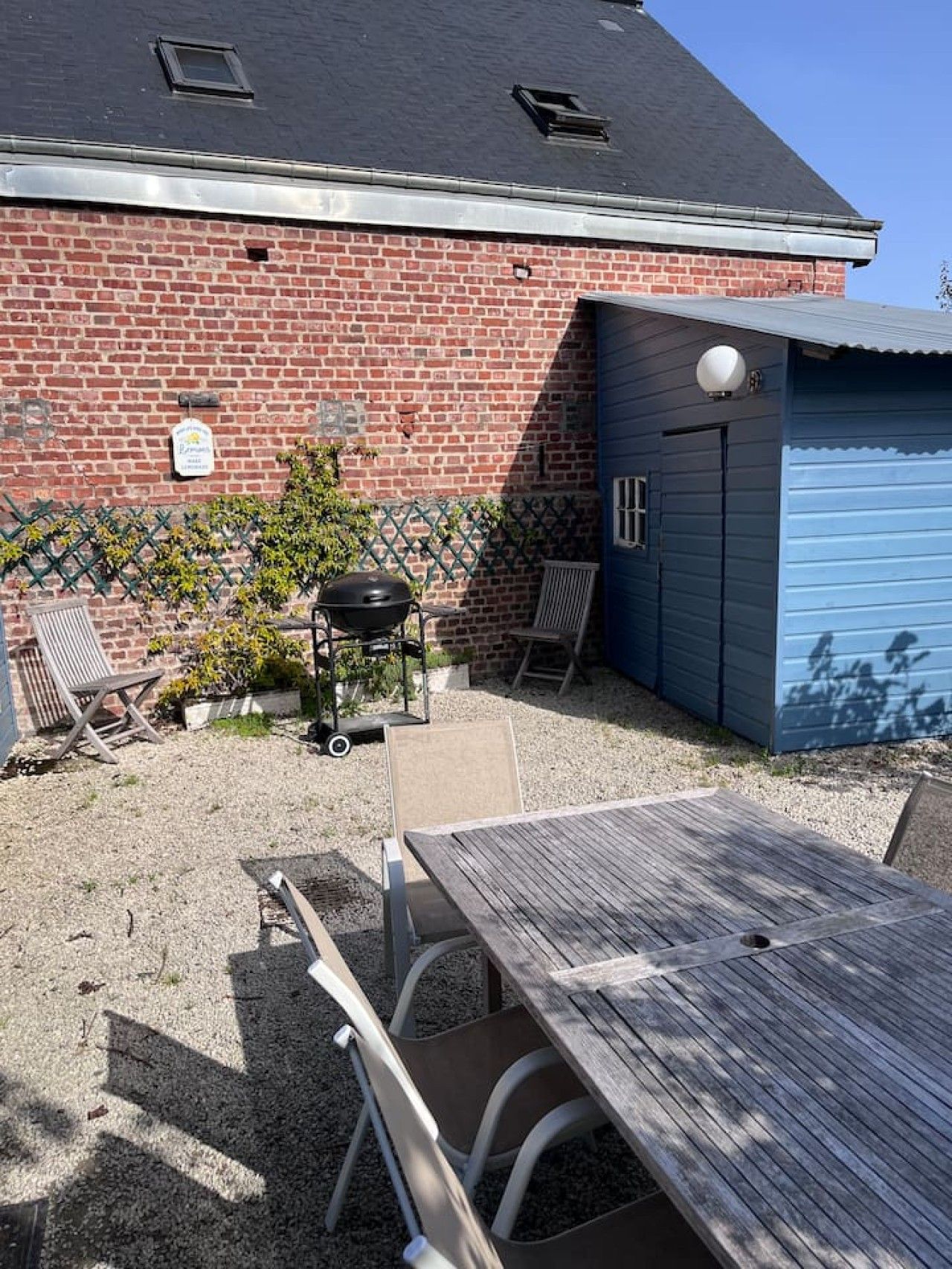 A patio area with a table and chairs, a barbecue grill, and a blue garage door.