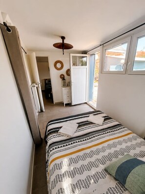 Quarto com cama, janela, porta e ventilador de teto.
