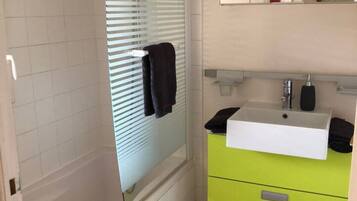 A bathroom with a white sink, green cabinet, and a mirror above the sink.