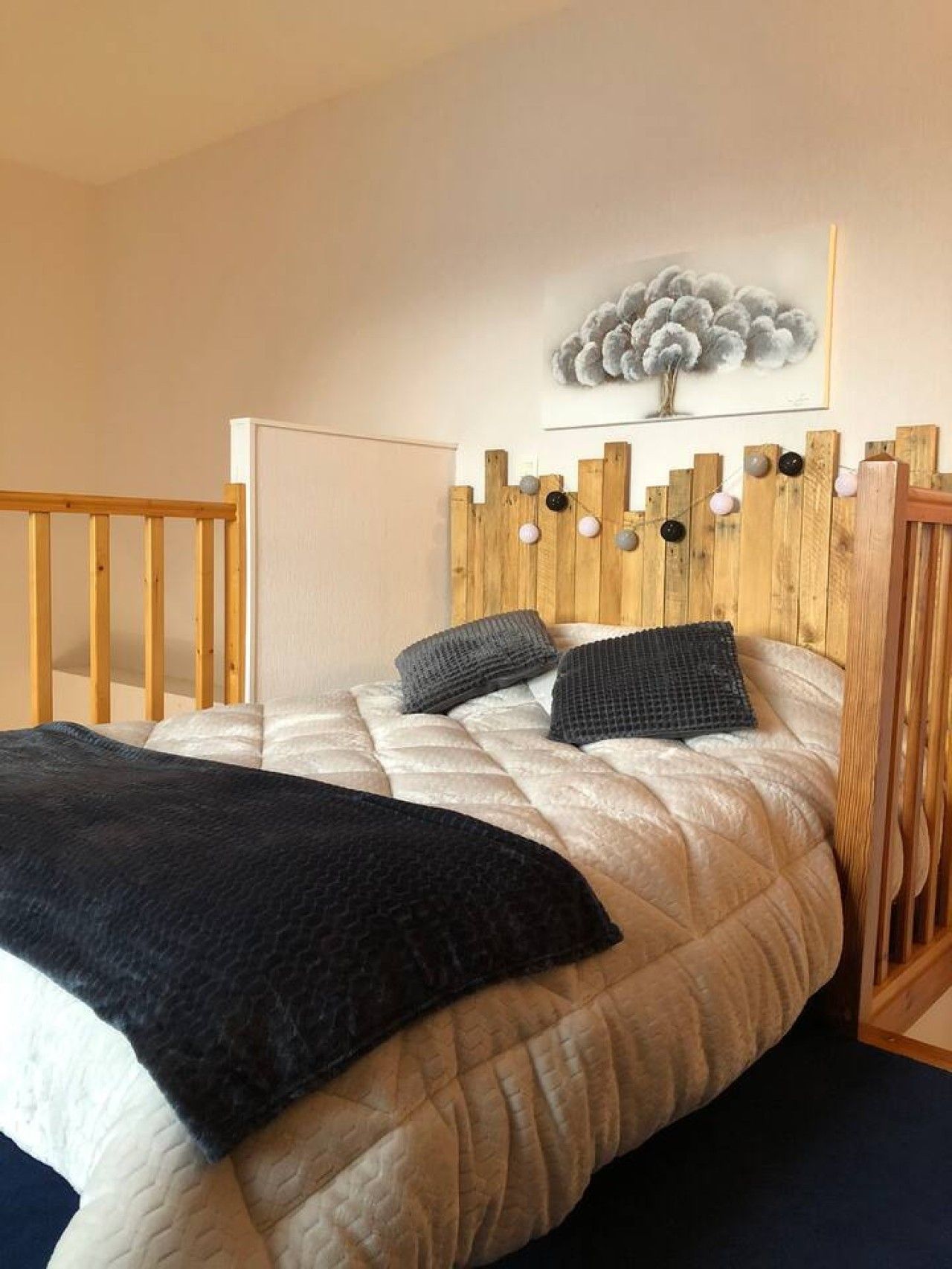A bedroom with a wooden headboard, a quilted bedspread, and a black throw blanket.