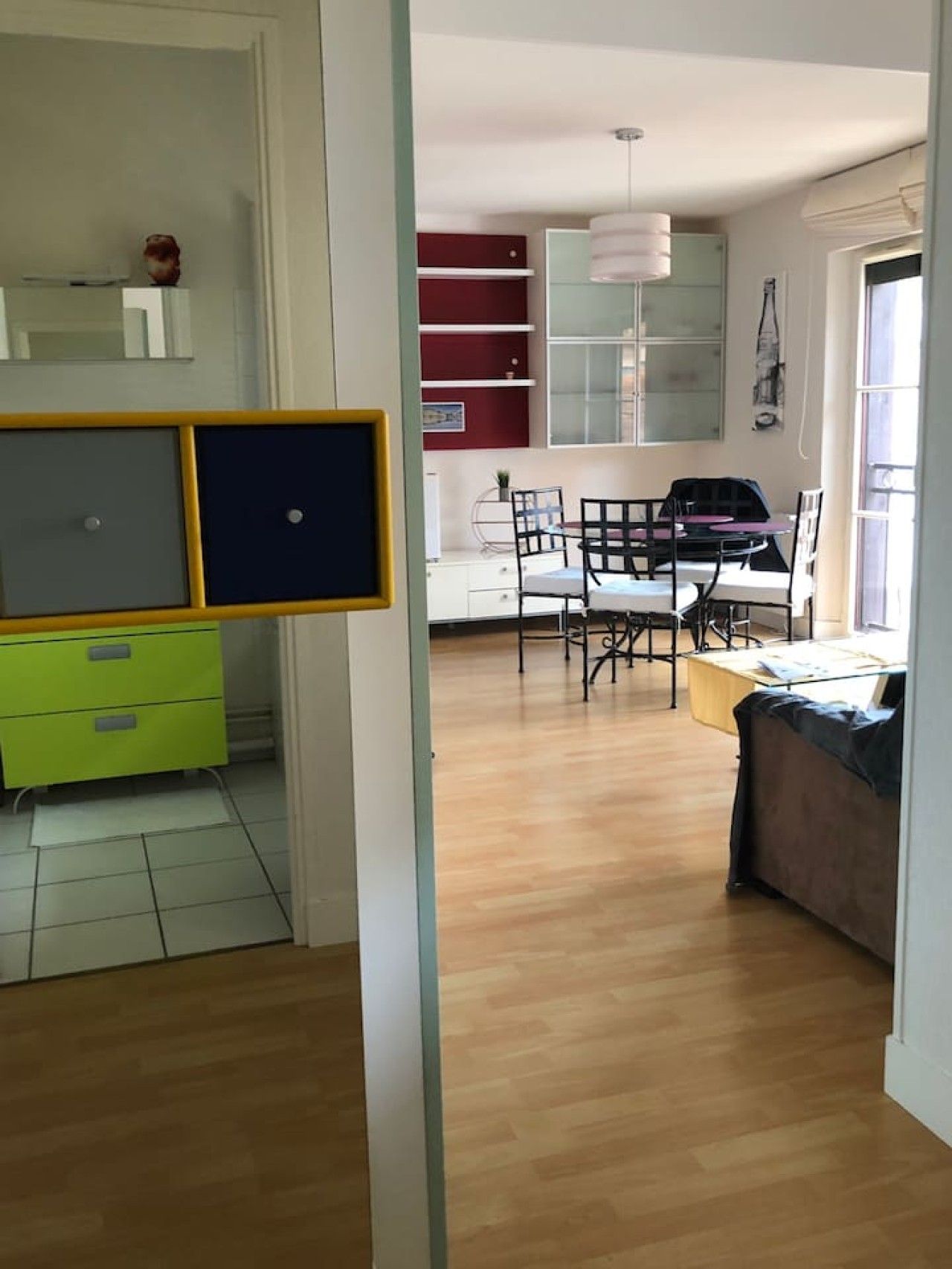 A room with a dining table, chairs, a sofa, and a small cabinet.