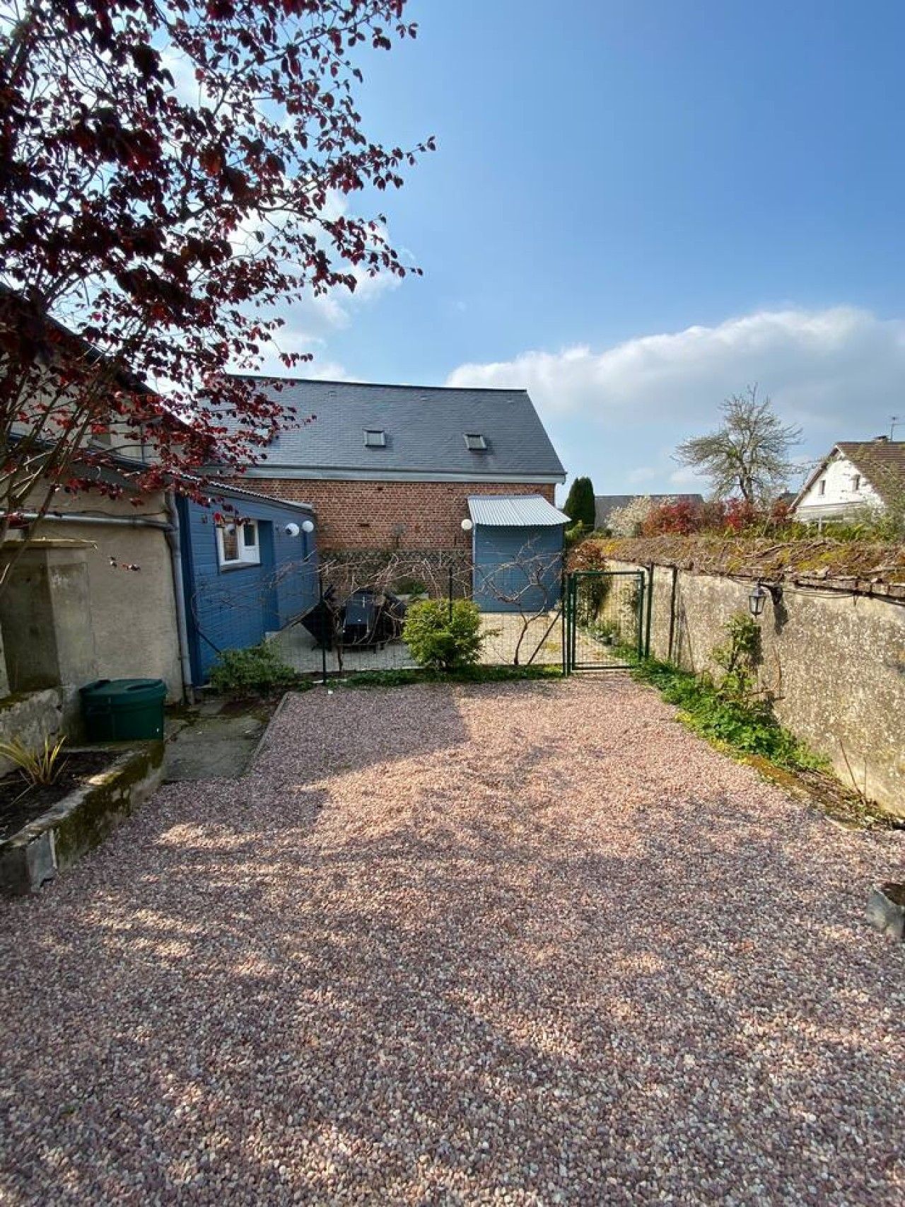 Een grindpad dat leidt naar een huis met een bakstenen gevel en een blauwe garage.