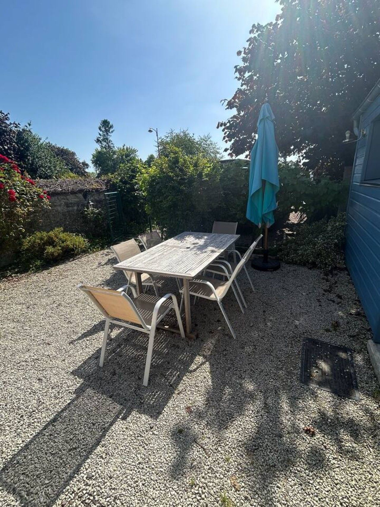 An outdoor patio with a table and chairs, surrounded by gravel.