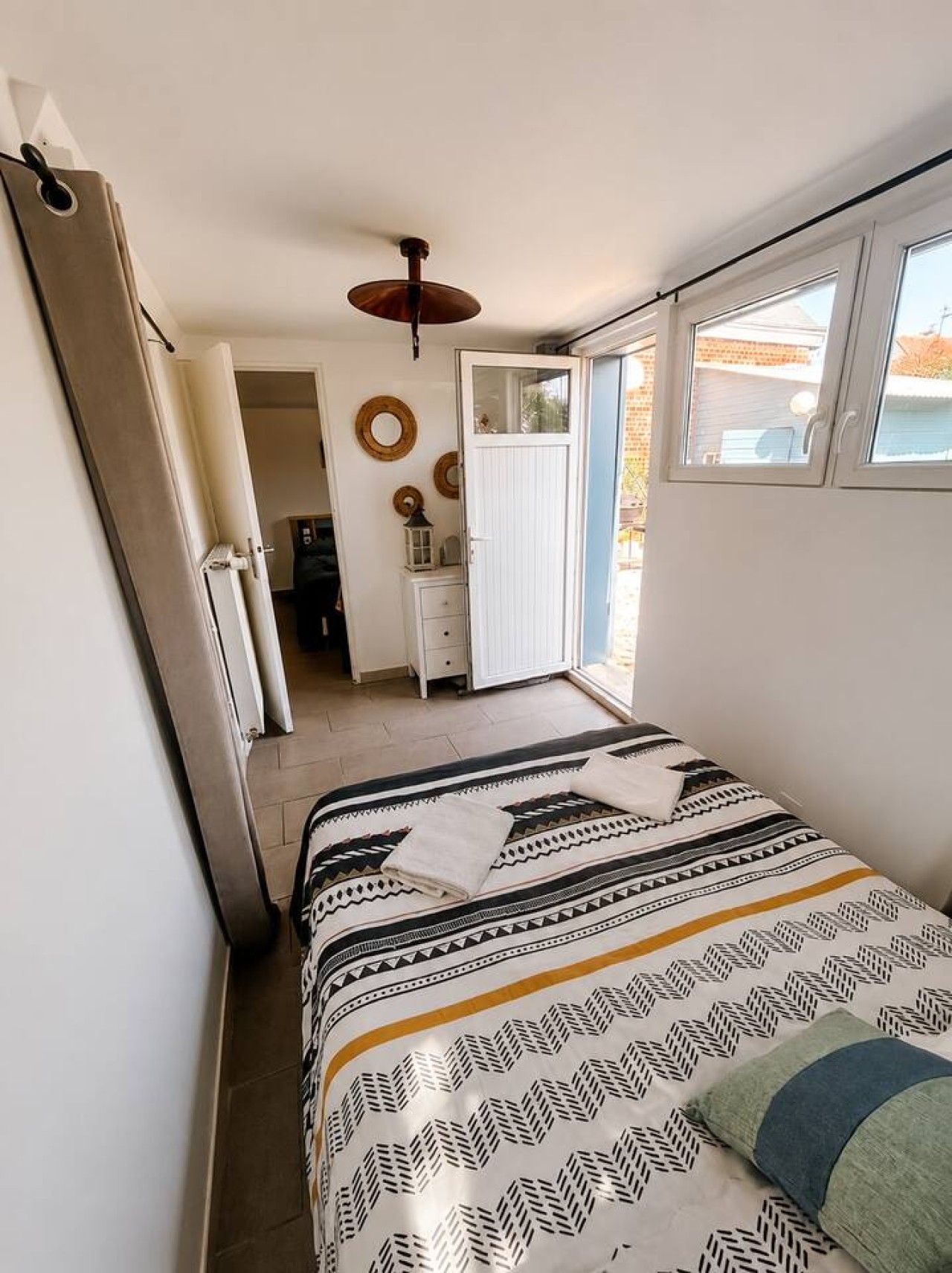 A bedroom with a bed, a window, and a door leading to a bathroom.